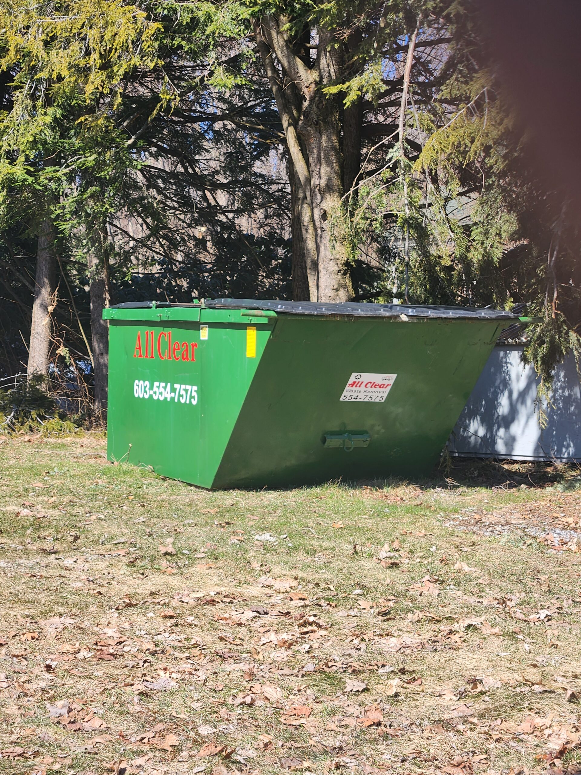 Large All Clear dumpster next to fence